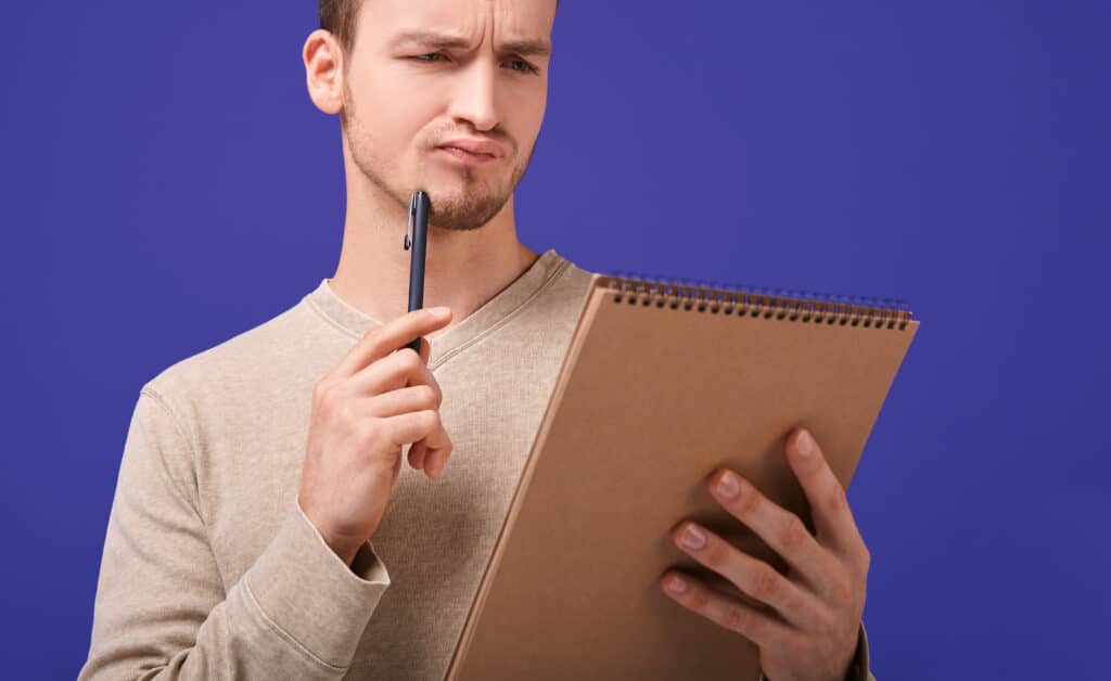 thinking man with a brown paper notebook looks at page
